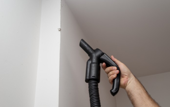 Person using a vacuum to clean the wall