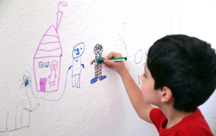 Child drawing on the wall with crayons