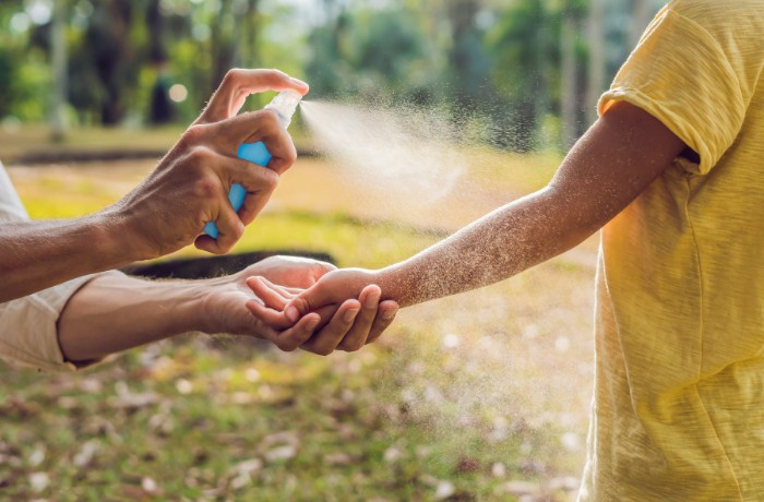 person-spraying-mosquito-repellant-to-kids-arm